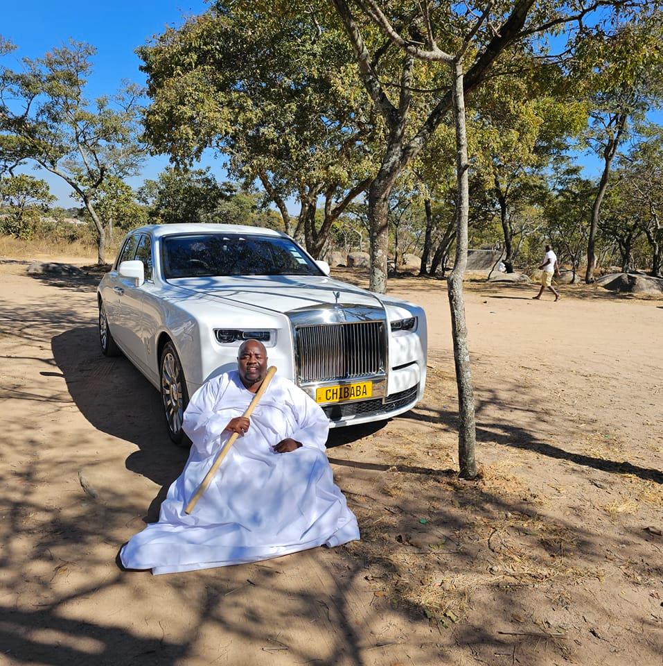 Sir Wicknell in church regalia in front of Rolls Royce
